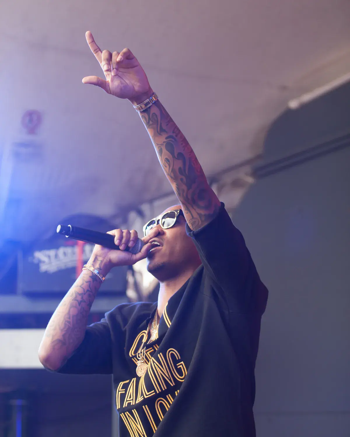 Future in sunglasses raps into a microphone with one hand raised