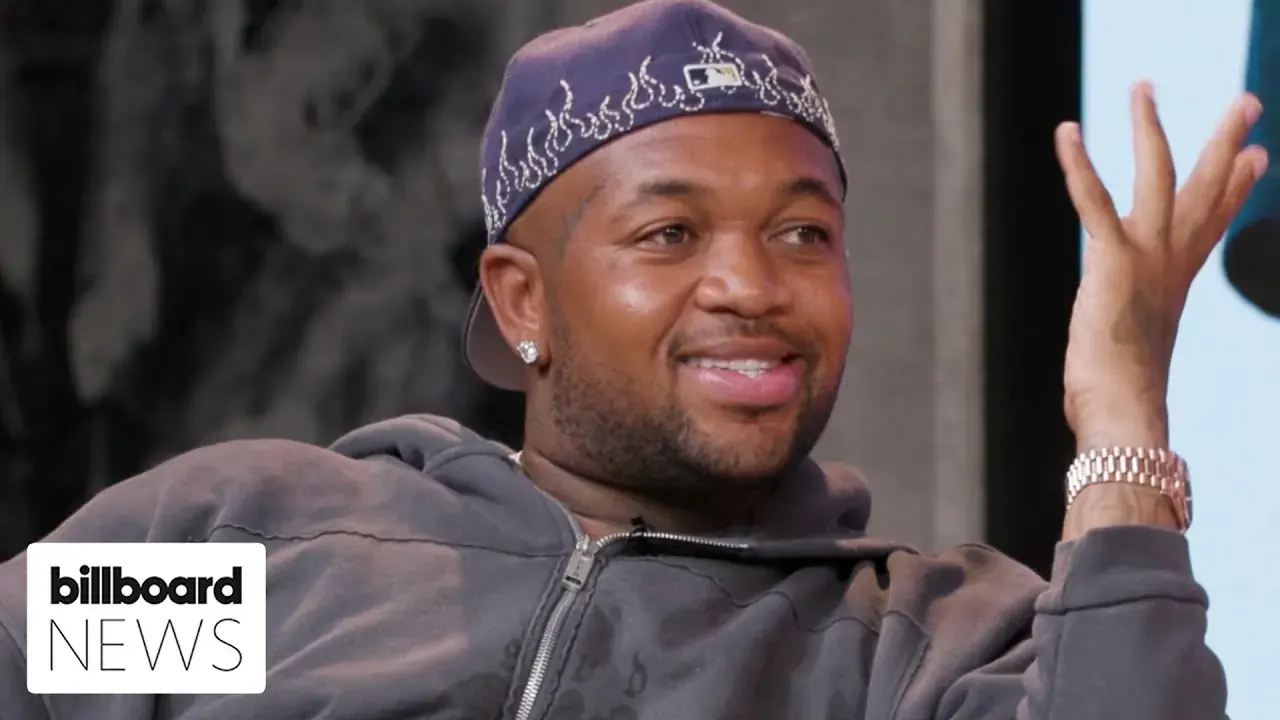 Mustard smiling and gesturing during a Billboard News interview