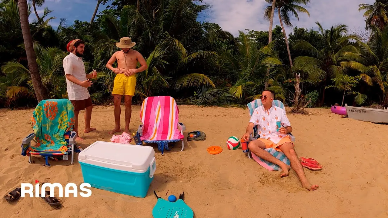 Three men on a tropical beach with striped chairs and a cooler
